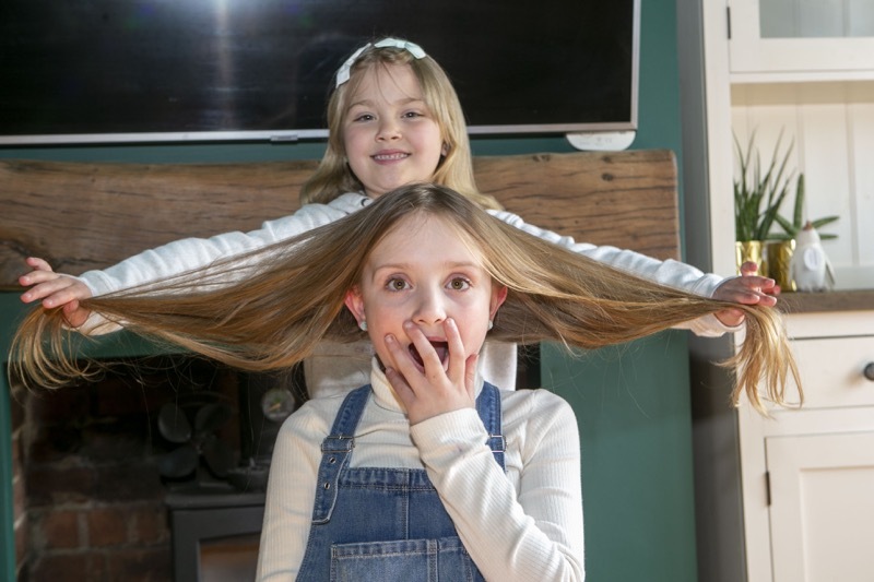 Pending Haircut: nine years old Meridith Price who is due to have her hair chopped in memory of her friend, is having her hair checked by her sister felicity for good measure. Picture Shaun Colborn PD092068
